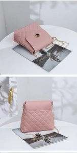 Macro detail of pink quilted bucket bag with gold heart clasp and metal chain strap