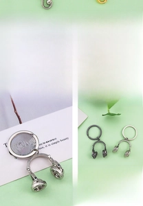 Detail of creative headphone keychains in silver and gunmetal finish on mint background