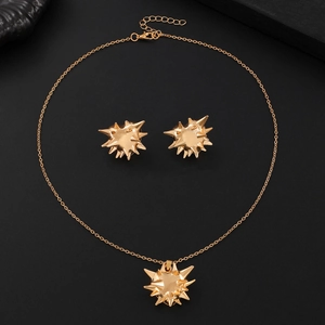 Detail of gold spike jewelry set featuring sunburst pendant necklace and matching earrings