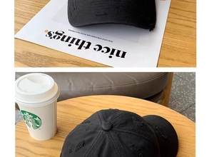Detailed macro view of distressed black cotton baseball cap with ripped brim effects
