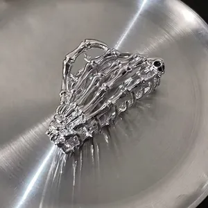Macro shot of silver bone-shaped metal hair claw clip on a brushed metal tray