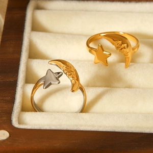Close-up of adjustable 18K gold and two-tone stainless steel star moon rings on velvet