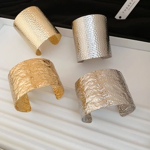Detail of gold and silver irregular textured open bangles on a decorative tray