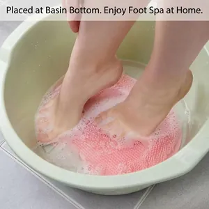 Pink silicone foot massage mat for bath use in a washbasin with foamy water