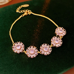Macro shot of gold-plated flower bracelet with purple zirconia on green velvet