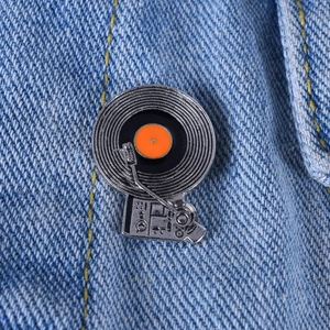 Macro shot of retro vinyl record player enamel pin on blue denim jacket fabric