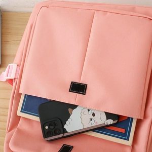 Close-up of pink backpack front pocket with velcro flap holding phone and books