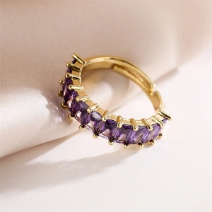 Macro shot of adjustable gold ring featuring a purple step-cut zircon on silk