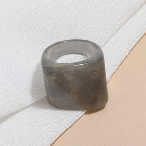 Macro shot of wide marble textured resin ring with subtle gold flecks on white fabric