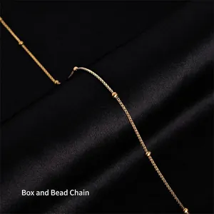Macro shot of gold-plated titanium box chain with metal beads on black silk fabric