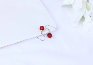 Detailed view of red agate round bead earrings with S925 silver hooks on a white tray