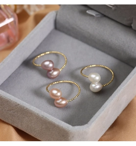 Detailed view of white, pink, and purple freshwater pearls on golden beaded rings