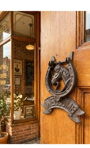 Nahaufnahme der Vintage-Pferdekopf-Türklopfer aus Gusseisen mit Welcome-Schild
