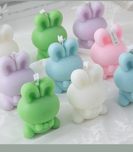 Detailed close-up of pastel bunny scented candles on a white lace fabric background
