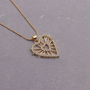 Macro detail of a gold heart pendant necklace with rhinestones and snake chain