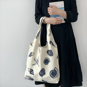 Detail of cream canvas tote bag with blue shell print and spacious interior for books