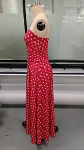 Detail of red polka dot maxi dress featuring elegant side ruching and slimming waistline