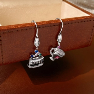 Macro view of asymmetrical cupcake earrings with colorful zircon stones on leather box