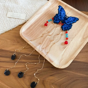 Gros plan d'épingle à cheveux papillon bleu brodé avec pompons dorés et perles
