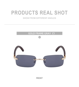 Front view of rimless rectangular sunglasses with gold metal frame and grey lenses