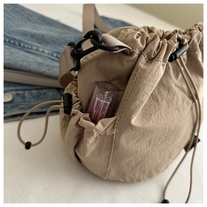 Detail der beigen Nylon-Beuteltasche mit Seitentasche und robustem Karabinerhaken