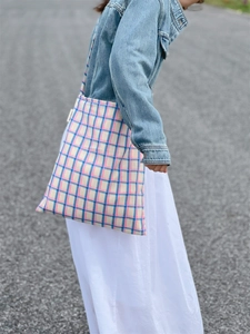 Detail of pink and blue plaid cotton tote bag showing texture and side woven label