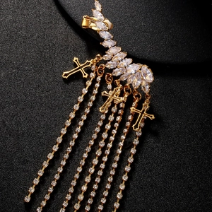 Goldene Kreuz-Fransenohrringe mit funkelnden Marquise-Zirkonia auf schwarzem Hintergrund