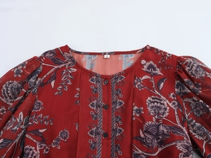 Detail of red floral chiffon blouse featuring neckline buttons, size S tag, and puff sleeves
