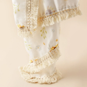 Detail of sunflower print baby blanket with decorative beige crochet tassel fringe