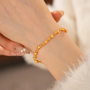 Detail of 24k gold plated beaded bracelet with matte and faceted metallic beads on wrist