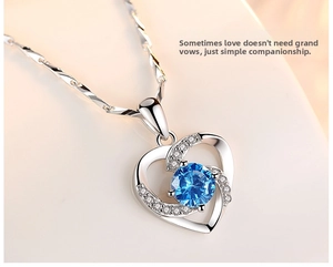 Macro detail of silver heart necklace with blue center stone and sparkling small diamonds