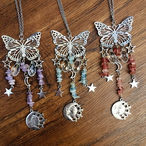Three butterfly suncatchers with crystals and moon charms on a rustic wood background