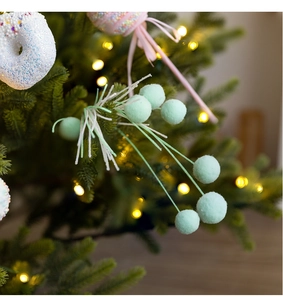 Close-up of mint green flocked ball sprig and white donut ornament on Christmas tree