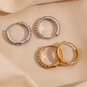 Macro detail of 18K gold plated heart hoop earrings with micro-set zircon on silk cloth