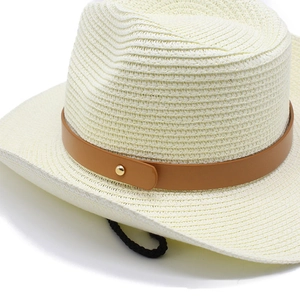 Dettaglio di cappello in paglia beige con nastro in ecopelle marrone e sottogola
