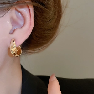 Close-up of golden multi-layer metal ear clips worn by a model in a minimalist style
