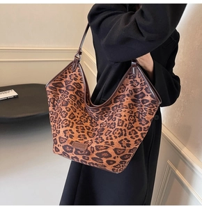 Detail of leopard print tote bag with brown leather trim and slim shoulder strap