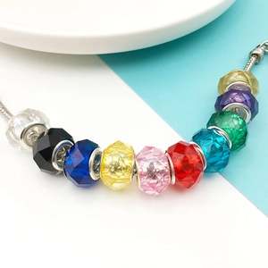 Close-up of faceted resin beads on a silver snake chain bracelet in various vibrant colors