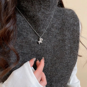 Detail of silver horse pendant necklace worn over a dark grey knitted sweater