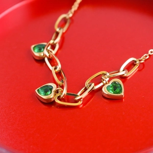 Gold-plated necklace with three green heart-shaped gemstones on oval link chain