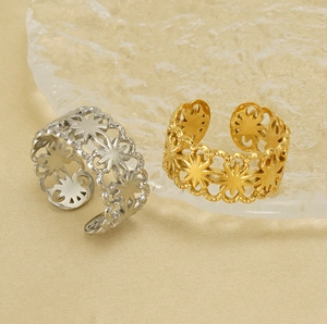 Detailed view of hollow star flower rings in gold and silver over glass props