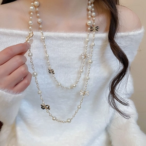 Detail view of French vintage layered pearl necklace with bow accents on model