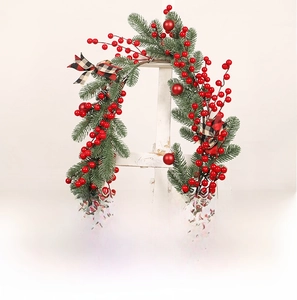 Detail of Christmas garland with red berries, pine needles and checkered bow decor