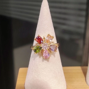 Detail of flower shaped ring with colorful zircon stones on white conical display stand