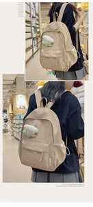 Khaki minimalist backpack side view with plush pendant and drawstring pocket detail