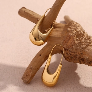 Détail de boucles d'oreilles en U plaquées or 18 carats sur une branche décorative