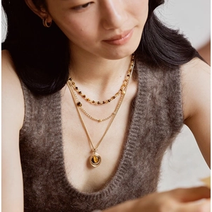 Collana a tre strati d'oro con pendente rotondo in occhio di tigre su una modella