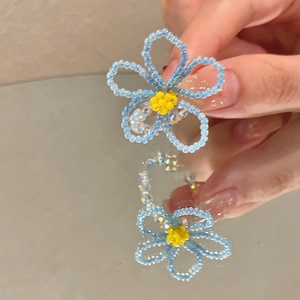 Détail d'une bague fleur en perles de cristal bleu faites à la main avec centre jaune