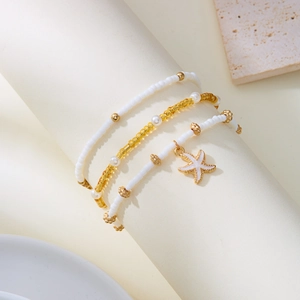 Multilayer beaded necklace and bracelet set featuring a gold starfish pendant and white beads