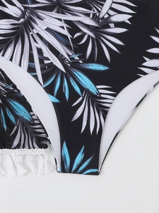 Détail d'un bikini à imprimé feuilles de palmier avec des pompons blancs décoratifs au bord